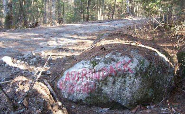 large rock with adirondack painted on it in red letters