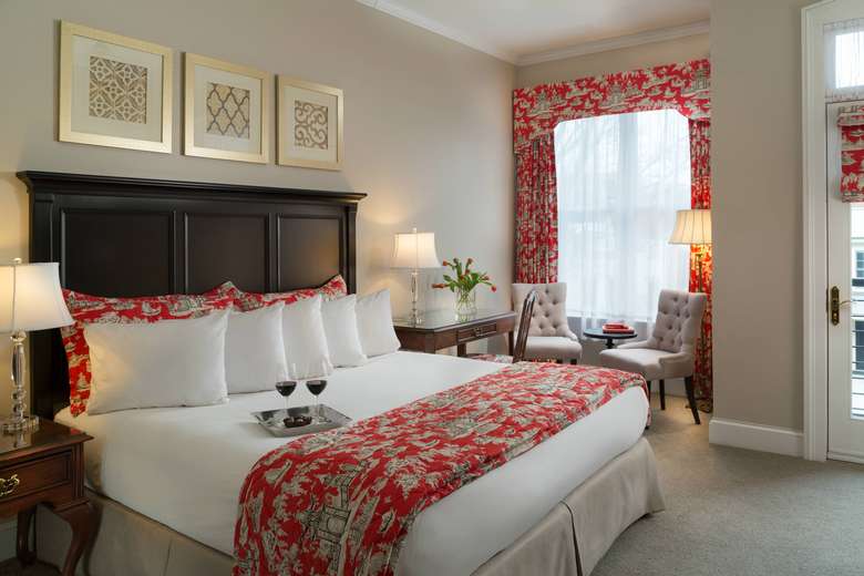 king-size bed in a bed and breakfast with white bedding and red/pink accents