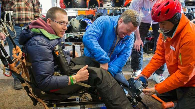 A young man getting fitted for adaptive ski equipment