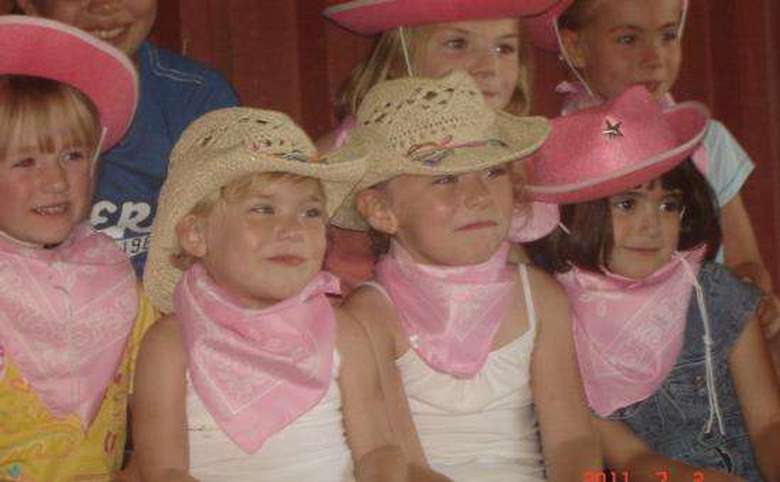 four young kids wearing cowboy hats and pink bandanas