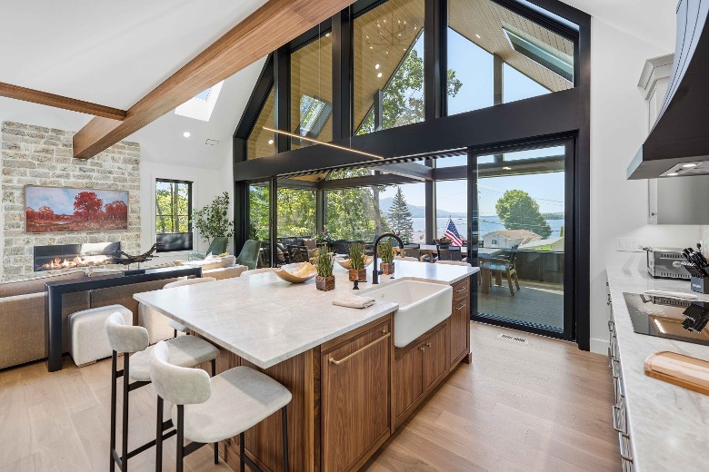 a large open floor plan kitchen and living room with large doors and windows facing the outdoors