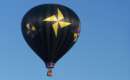 black hot air balloon with yellow pinwheels in flight