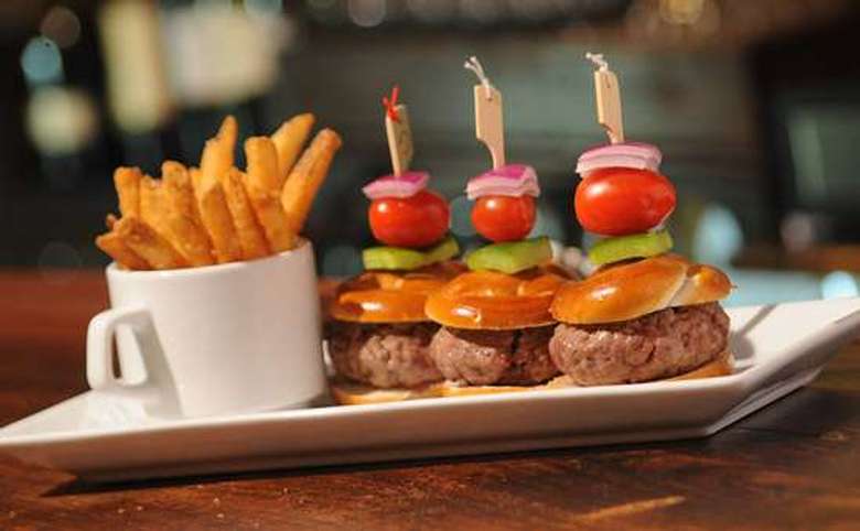 trio of burger sliders with a white mug of french fries