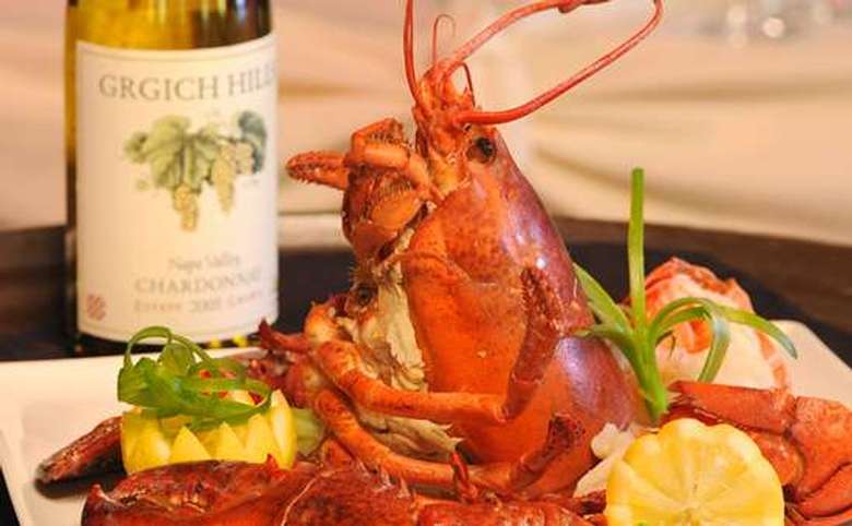 steamed lobster with lemon garnish and a bottle of white wine in the background