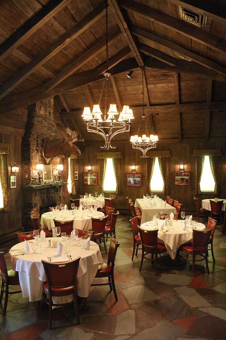 dining room at the wishing well restaurant with round tables, red chairs, and a hanging light fixture