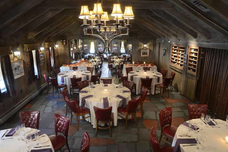 dining room at the wishing well restaurant with round tables, red chairs, and a hanging light fixture