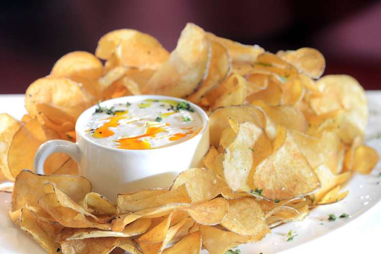 cup of hot dip with chips surrounding it