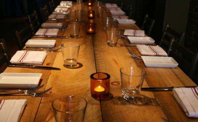 large wooden table with napkins and empty glasses at each seat