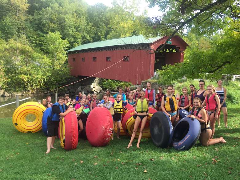 group of kids in life jackets holding inner tubes