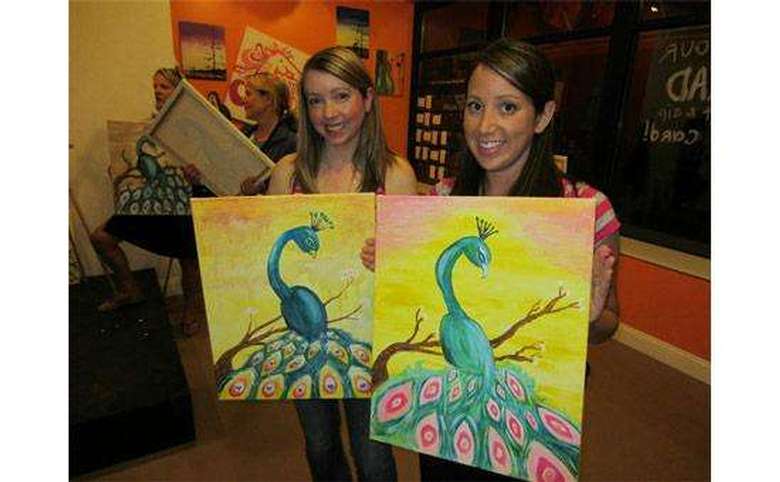 two people posing with paintings after doing a paint and sip