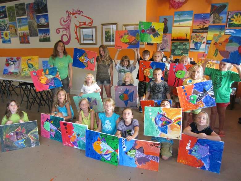 group of people posing with paintings after doing a paint and sip