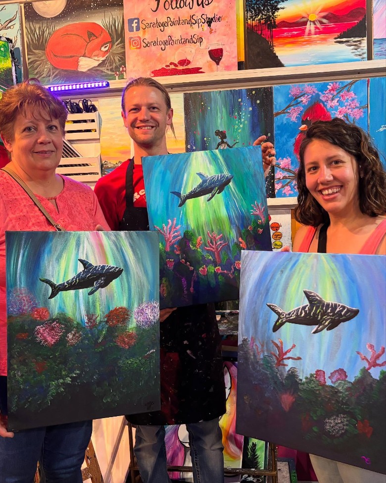 three people holding up their artworks in a studio