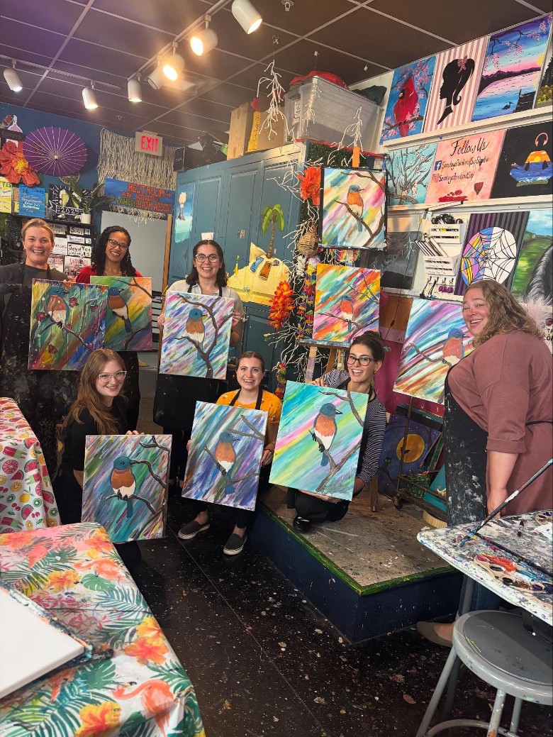 people holding up their artworks in a studio