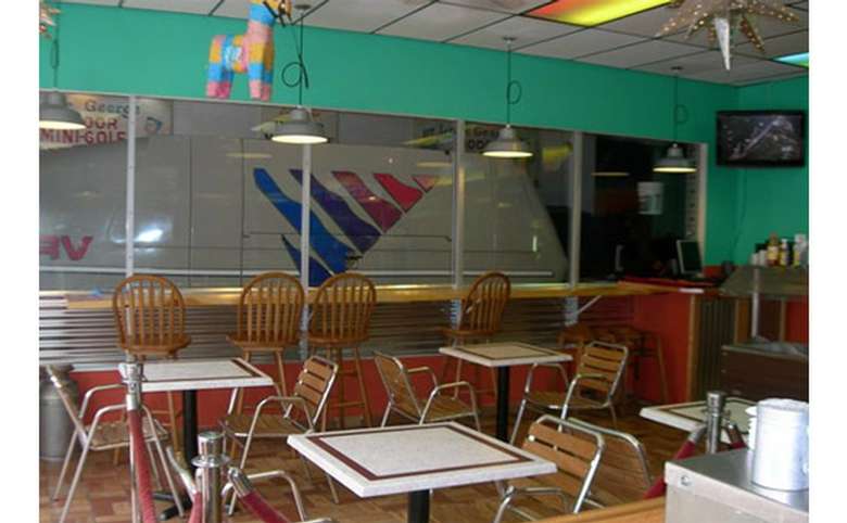 Interior dining area with tables and chairs, as well as a long counter with high-top chairs