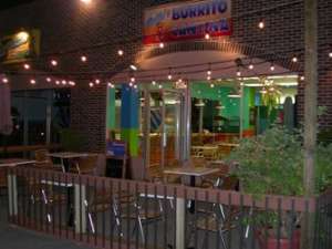 The entrance to Pablo's Burrito Cantina in the evening. There are patio lights over an outdoor patio with several tables and chairs.