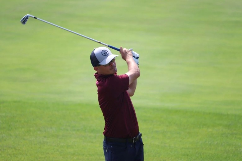 a man swinging a golf club on a grassy course