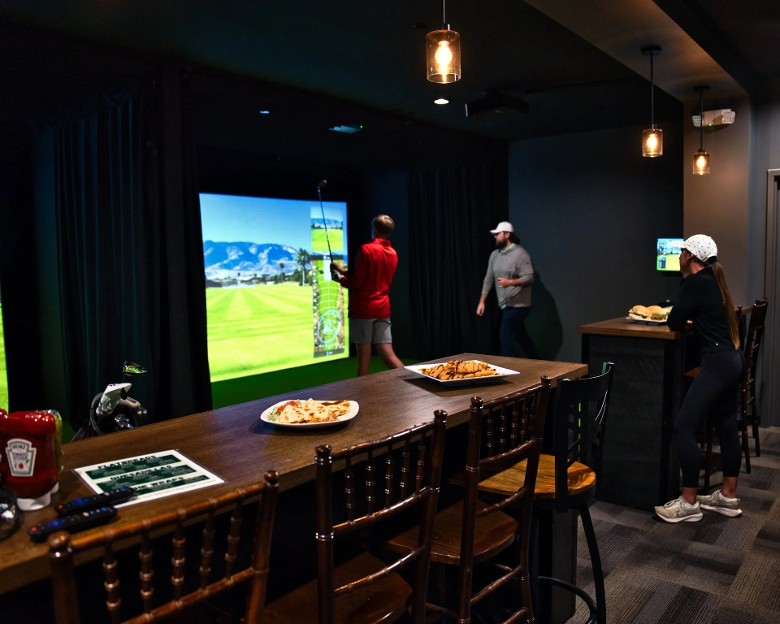 a group of people at indoor golf simulators