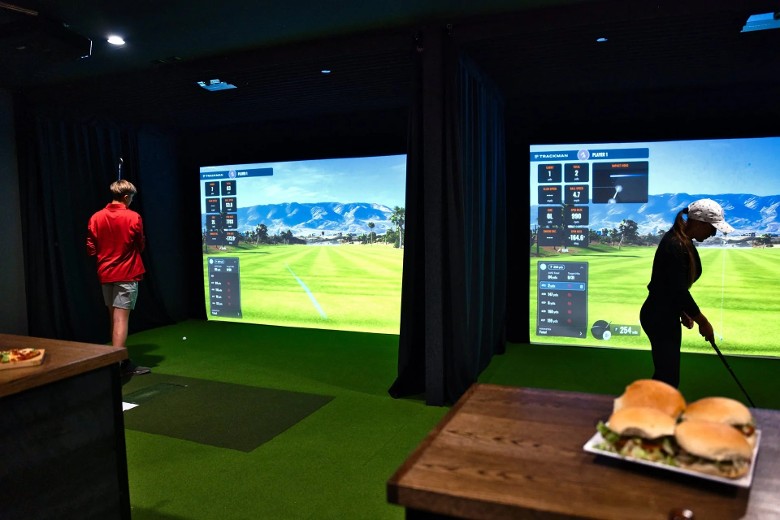 two people at indoor golf simulators