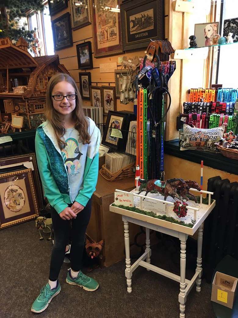 girl standing next to a rack of colorful dog leashes