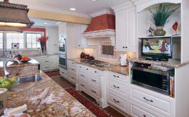 kitchen with white cabinets and drawers, with a microwave and tv at one end