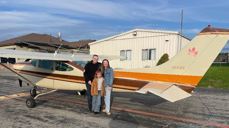 parents and kid pose by small plane