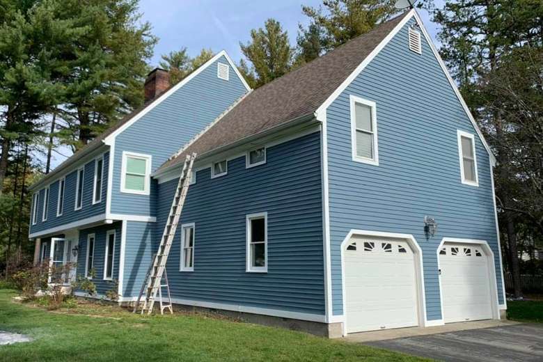 blue house with white window frames and two garage doors