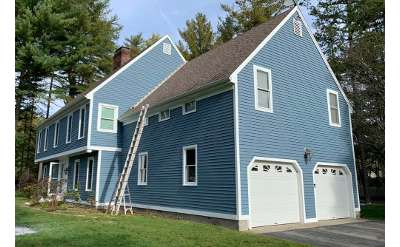 blue house with white window frames and two garage doors