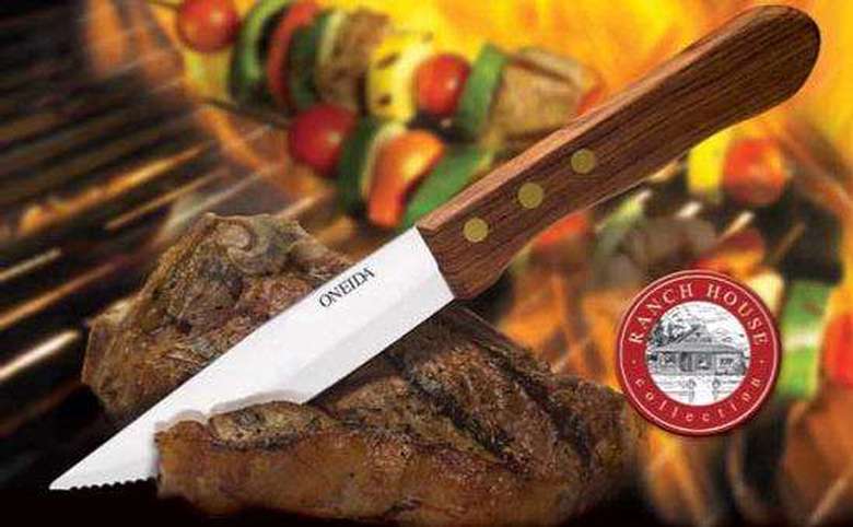knife slicing steak with kabobs on the grill in the background