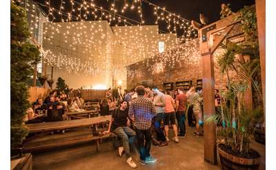 groups of people on an outdoor patio with string lights hanging overhead