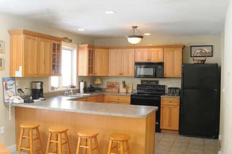 kitchen with light brown cabinets and four wooden barstools