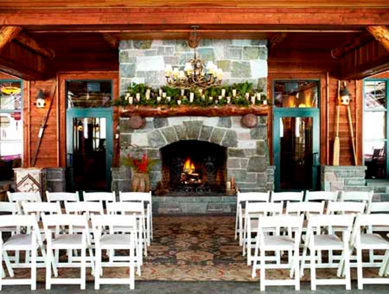 a small number of white chairs set up for a wedding ceremony in front of a stone fireplace