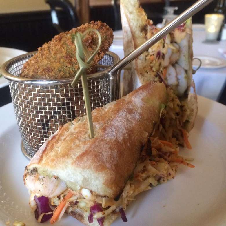 triangular sandwich with a basket of something fried behind it
