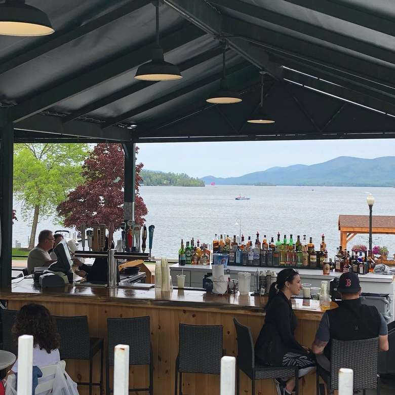 people seated at an outdoor bar overlooking a lake