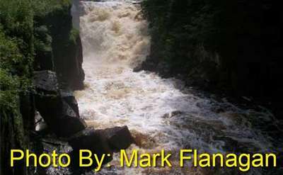 brown waterfall rushing into a pool with photo credit to mark flanagan