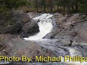 narrow, shallow waterfall winding between rocks with photo credit to michael phillips