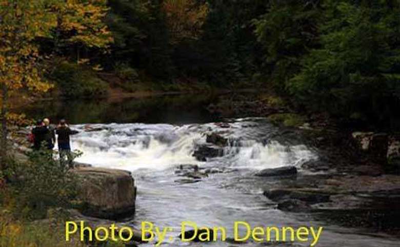 three people taking a picture of a small waterfall with photo credit to dan denney