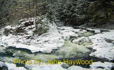 river flowing around rocks in the winter with photo credit to john haywood