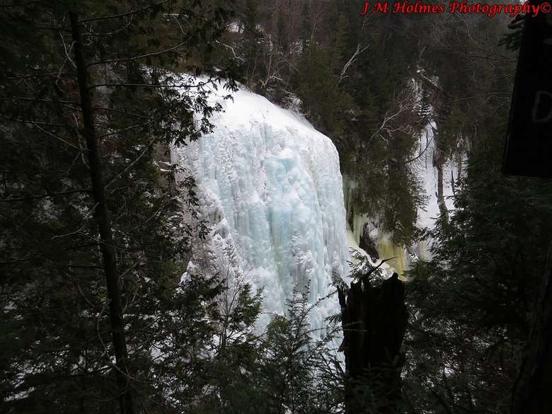 frozen waterfall in the woods with photo credit to j.m. holmes photography