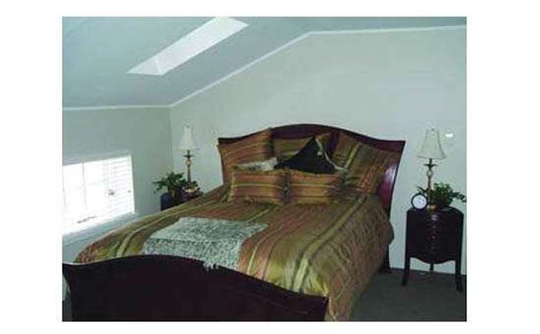 bed with a striped comforter in a room with sloped ceilings and a skylight