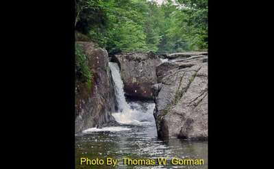 waterfall spouting between two rocks with photo credit to thomas w. gorman