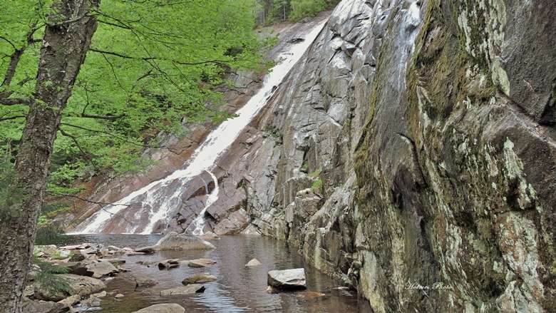 view from below of a steep waterfall sliding down a rock face