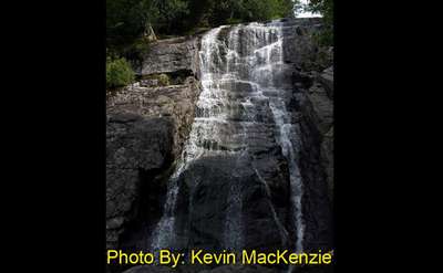 tall waterfall dropping down multiple tiers of rocks with photo credit to kevin mackenzie