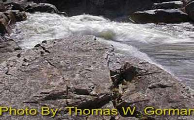 water splashing up against rocks with photo credit to thomas w. gorman
