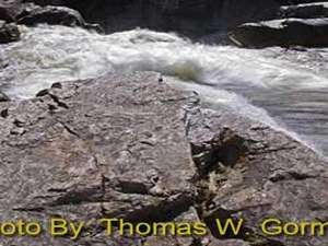 water splashing up against rocks with photo credit to thomas w. gorman