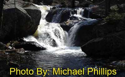 small waterfall flowing around and over rocks with photo credit to michael phillips