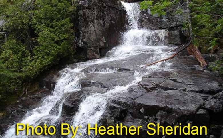waterfall flowing over rocks with photo credit to heather sheridan