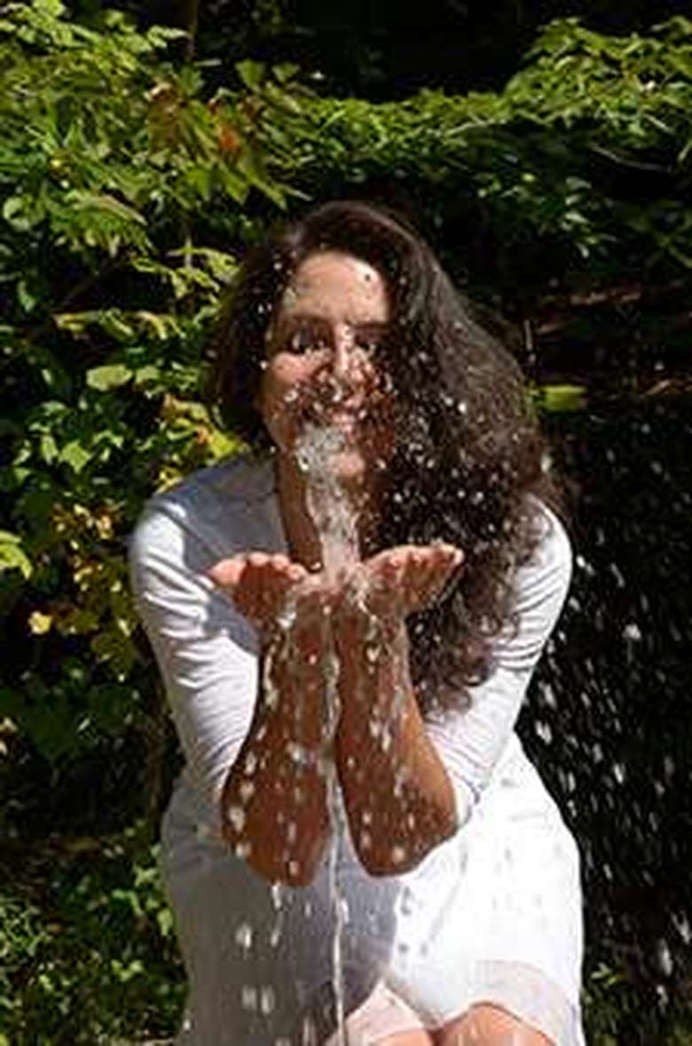 woman with her hands extended catching the water from a mineral spring