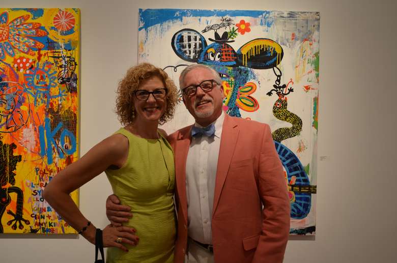 man and woman standing in front of two bright paintings