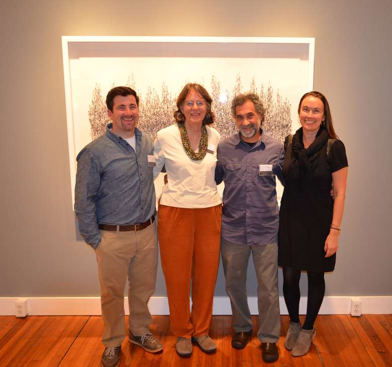 four people standing in front of a piece of art