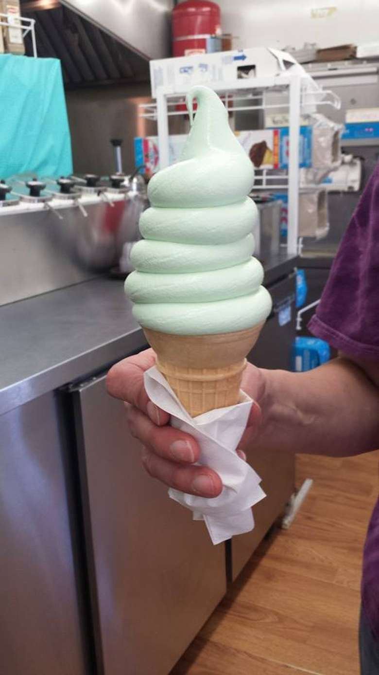 a hand holding a cone of soft serve ice cream